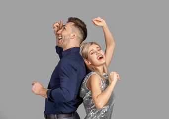 Happy dancing young couple on grey background