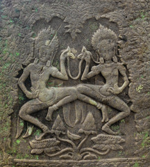 Two dancing apsara, an old ornament on the ancient wall with moss, Angkor Wat, Cambodia