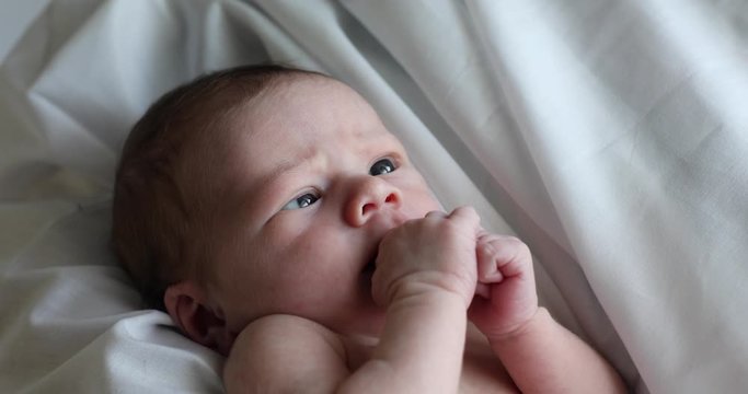 Newborn baby crossing eyes sucking on hands with hicups 4k footage 