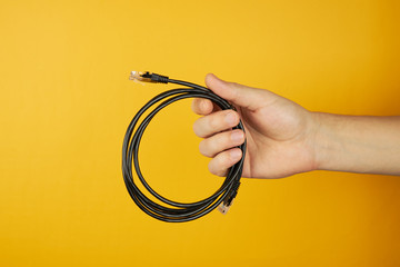 concept of network, internet, communications. hand holds cat 5e utp cable. Isolated on yellow...