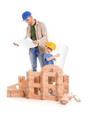 Father and little son dressed as builders playing with take-apart house on white background
