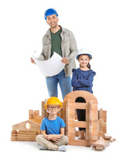 Father and little children dressed as builders playing with take-apart house on white background