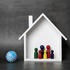 Coronavirus. Stay home, stay safe. Miniature house with family inside and coronavirus shape outside. Epidemic, social isolation, coronavirus COVID-19 concept.
