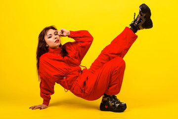 Modern girl in red overalls in the style of the 90s oversized clothes on a yellow background,...