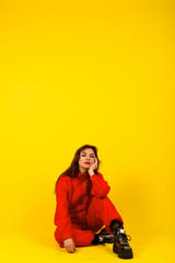 Modern girl in red overalls in the style of the 90s oversized clothes on a yellow background, expressive pose, fashion photo, trend 2020