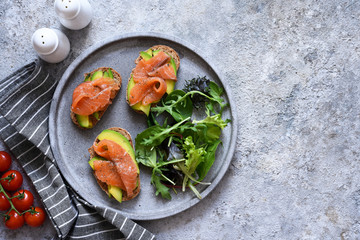 Toast with salmon and salad on a concrete plate, top view. Breakfast.