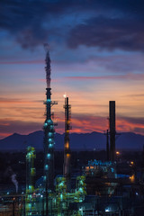 Fototapeta na wymiar Steam Smokestack and Flame at Refinery with Mountains and Sunset
