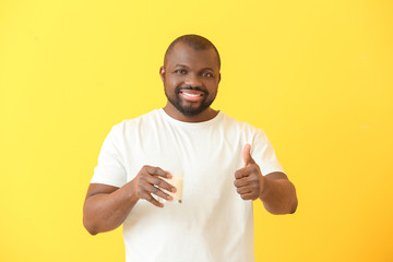Naklejka premium African-American man with milk showing thumb-up on color background