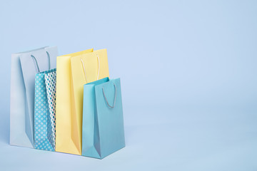 Trendy fashionable color shopping paper bags on light blue background. Spring sale, discounts,...