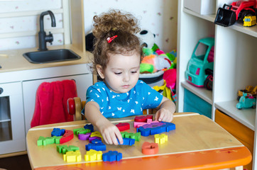 cute girl plays educational toys at home, collects the constructor, puzzle. motor development..