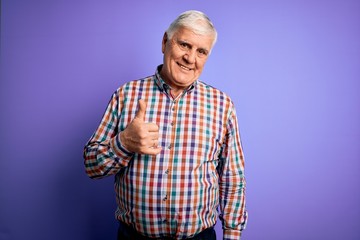 Senior handsome hoary man wearing casual colorful shirt over isolated purple background doing happy...
