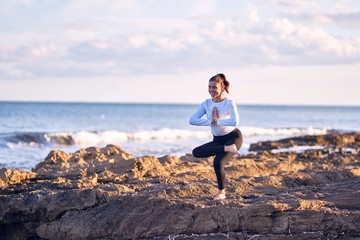 Young beautiful sportwoman practicing yoga. Coach teaching postures at the beach