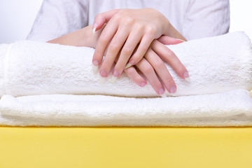 Obraz na płótnie Canvas Beautiful hands of young woman close-up on towel. Spa treatments for nails. Space for text. Woman holds hands on towel for manicure treatment procedure in spa salon.