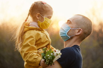 Family protection. A young father hugs his little girl daughter in the spring garden outdoors....