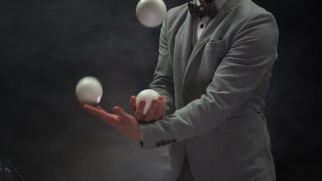 Closeup of hands in suit juggling white balls. Success and management