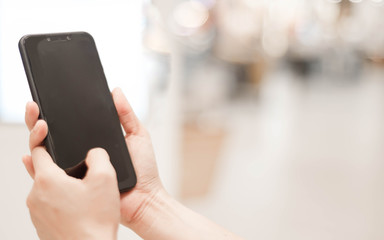 Female hands holding smart phone with blank blank screen for text message or information content,