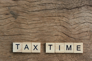 Tax time with wooden alphabet blocks, on plank wooden background with copy space.