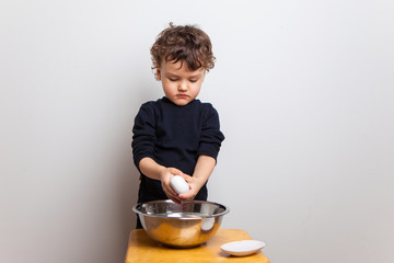 child, a boy in a black T-shirt washes his hands with soap on a white studio background.