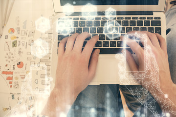 Double exposure of man's hands typing over computer keyboard and tech theme hologram drawing. Top view. Technology concept.