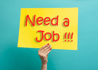 Hands holding a yellow paper banner with sign 