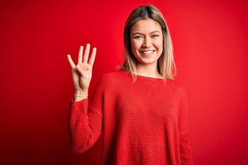 Young beautiful blonde woman wearing casual sweater over red isolated background showing and pointing up with fingers number four while smiling confident and happy.