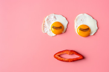 Pop art background. fried egg with eyelashes and strawberry lips on a pinkbackground. Food art....