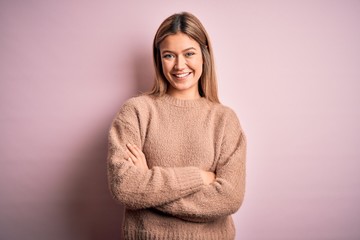 Obraz premium Young beautiful blonde woman wearing winter wool sweater over pink isolated background happy face smiling with crossed arms looking at the camera. Positive person.
