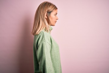 Young beautiful blonde woman wearing winter wool sweater over pink isolated background looking to...