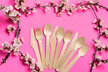 three sets of disposable tableware made of natural materials, wooden knife, spoon, fork. pink background with floral frame