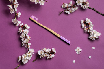 Obraz na płótnie Canvas natural bamboo toothbrush on a lilac background a frame of flowers. Zero waste concept. Eco friendly. 