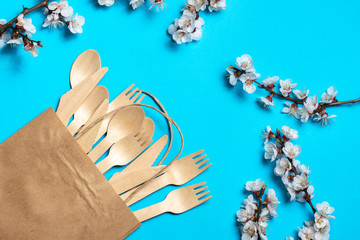 wooden spoons and forks in a craft bag on a blue background surrounded by white flowers