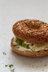 A bagel with cream cheese, avocado, blue cheese and microgreen