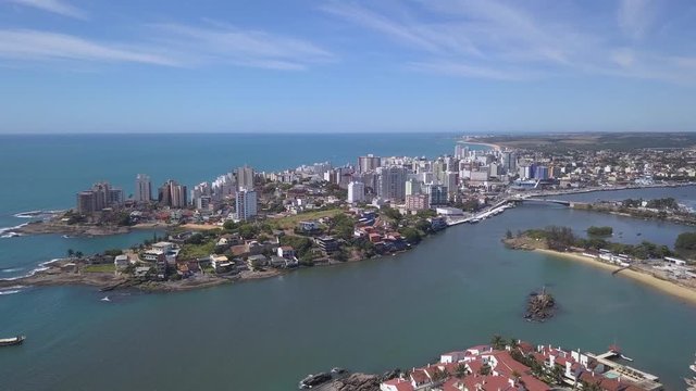 Beautiful drone view of Guarapari city center with beaches, houses and buildings on the waterfront streets and transparent sea on a sunny summer day with blue sky. Espirito Santo state, Brazil.4K