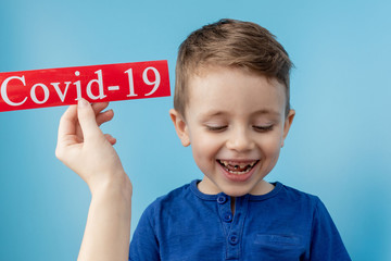 Little boy pointing to red paper with mesaage Coronavirus on blue background. World Health Organization WHO introduced new official name for Coronavirus disease named COVID-19