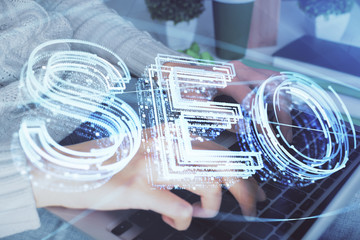 Double exposure of woman hands working on computer and seo hologram drawing. internet search...