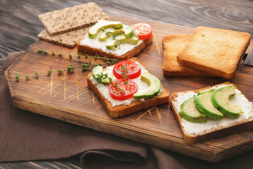 Board with tasty avocado sandwiches on table