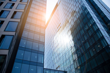 Skyscraper, modern building in the city with sunlight. Glass wall of an office building in the sunlight. Office building window close up with sunrise, reflection and perspective.