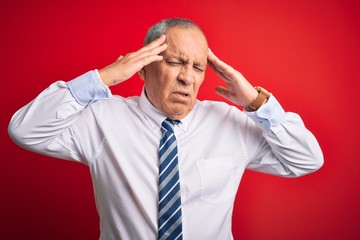 Senior handsome businessman wearing elegant tie standing over isolated red background with hand on head for pain in head because stress. Suffering migraine.