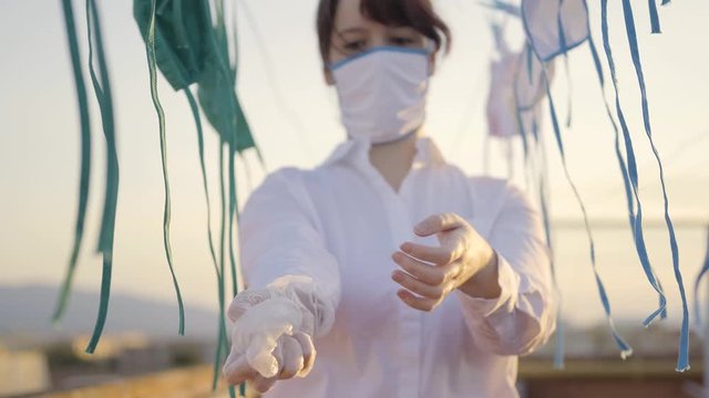 Young assistant shows and teaches the correct way to safely remove a pair of latex gloves. This girl is surrounded by clean, lying masks.