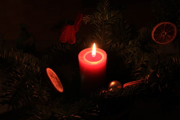 A burning candle on a decorated christmas tree.