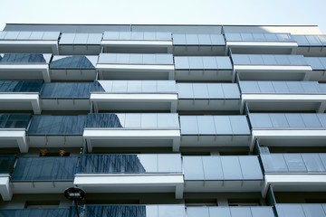 Beautifully designed multistory house with glass facade balconies in city district architecture, luxury real estate property apartments for sale.