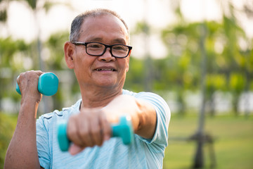 Asian old man doing physical exercise outdoor with dumbbells. Be healthy and strong, work on the...
