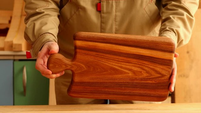 Woodworker showing dark cutting board from elm wood