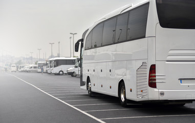 large tour bus rides along parked minibuses