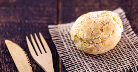 Brazilian cheese bread, on rustic wooden background with environmentally friendly bamboo cutlery.