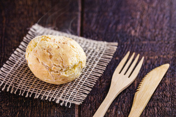 Brazilian cheese bread, on rustic wooden background with environmentally friendly bamboo cutlery.