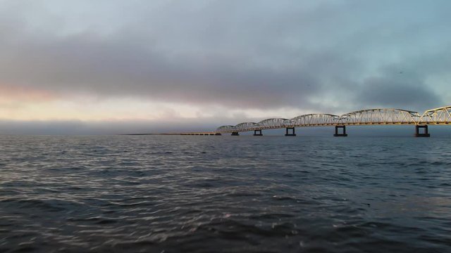 Drone Aerial astoria historic long bridge sunrise sunset evening clouds pushing forward low over waves of columbia river gorge