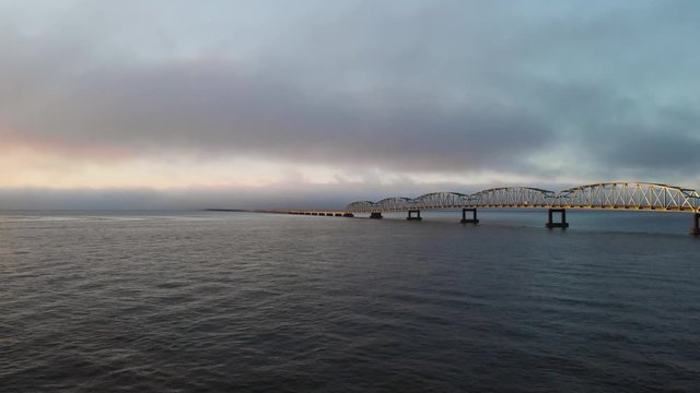 Drone Aerial astoria historic long bridge sunrise sunset evening clouds rising up over waves of columbia river gorge river
