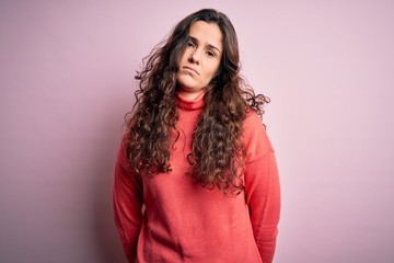 Young beautiful woman with curly hair wearing turtleneck sweater over pink background depressed and worry for distress, crying angry and afraid. Sad expression.