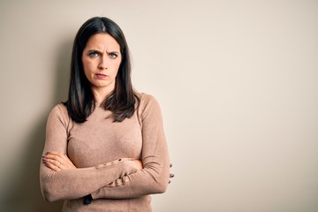 Obraz premium Young brunette woman with blue eyes wearing casual sweater over isolated white background skeptic and nervous, disapproving expression on face with crossed arms. Negative person.